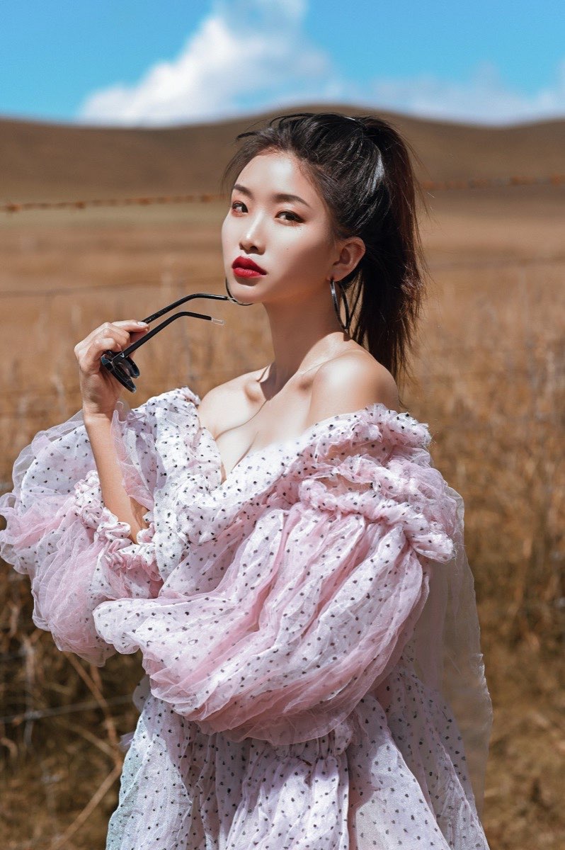Woman in a pale pink off-the-shoulder dress standing outdoors