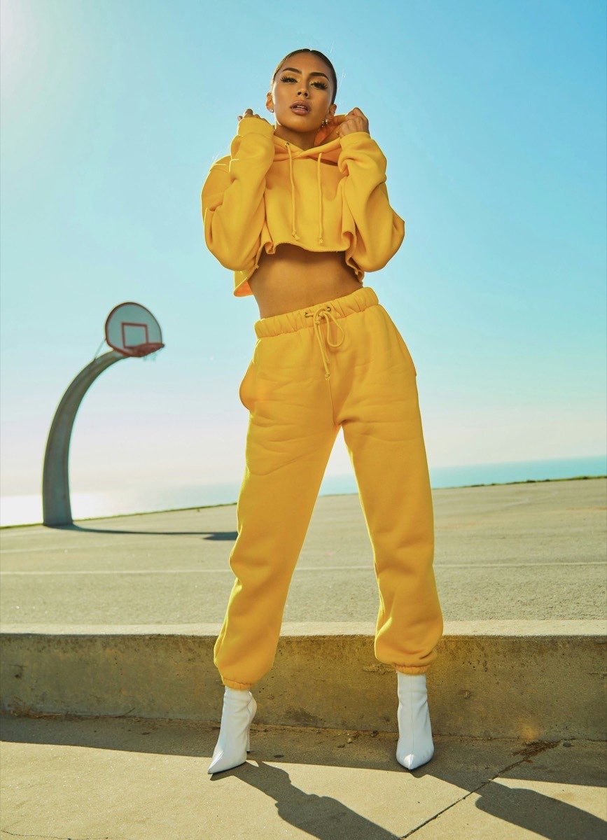 Woman wearing a yellow hoodie and matching trousers with white boots